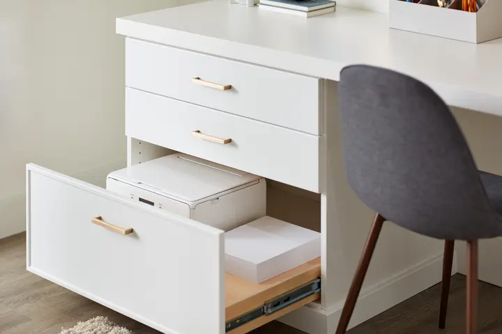 pull out drawers with golden knobs and white finish storing a printer 