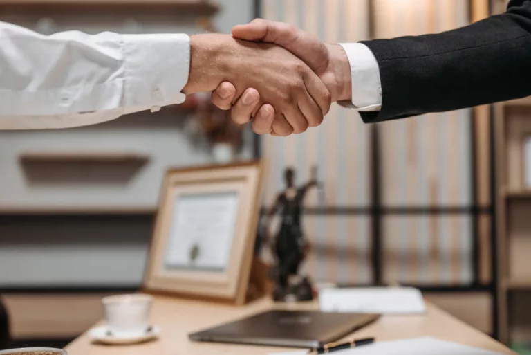 two people shaking hands above a table as a sign of making a business deal